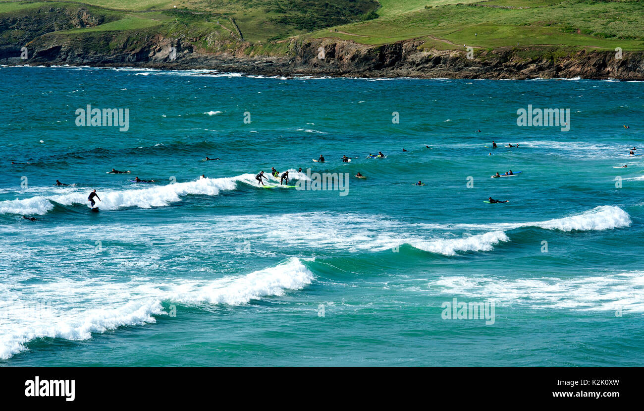 Surfers riding the waves of the Atlantic Ocean at Polzeath Bay in Cornwall, England. Stock Photo