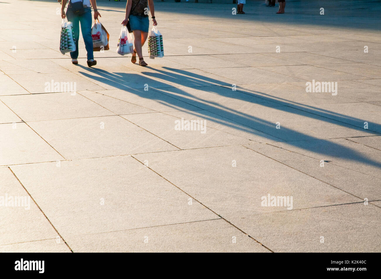 Two people walking and their shadows on the pavement Stock Photo - Alamy