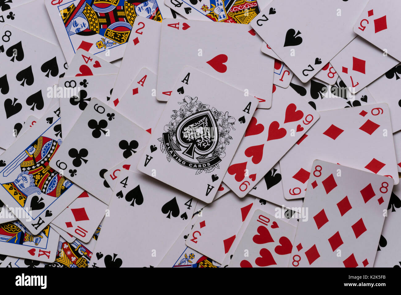 a deck of cards in a messy pile showing the Ace of Spades on top of the