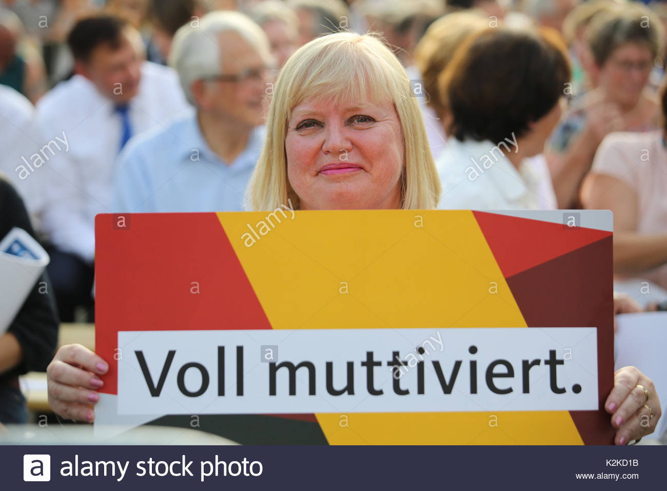 A clever gesture of support as a member of the CSU party in Erlangen, Germany, waits to hear Angela Merkel speak. Merkel is currently on the campaign  trail in the run up to the German election.The pun in the slogan refers to the German words for mother and motivated.Loosely translated it reads as 'fully mothervated' or 'very mammyvated' though the clever play on the instinctive German word Mutti and the word for motivated can only be fully appreciated in the original. Stock Photo