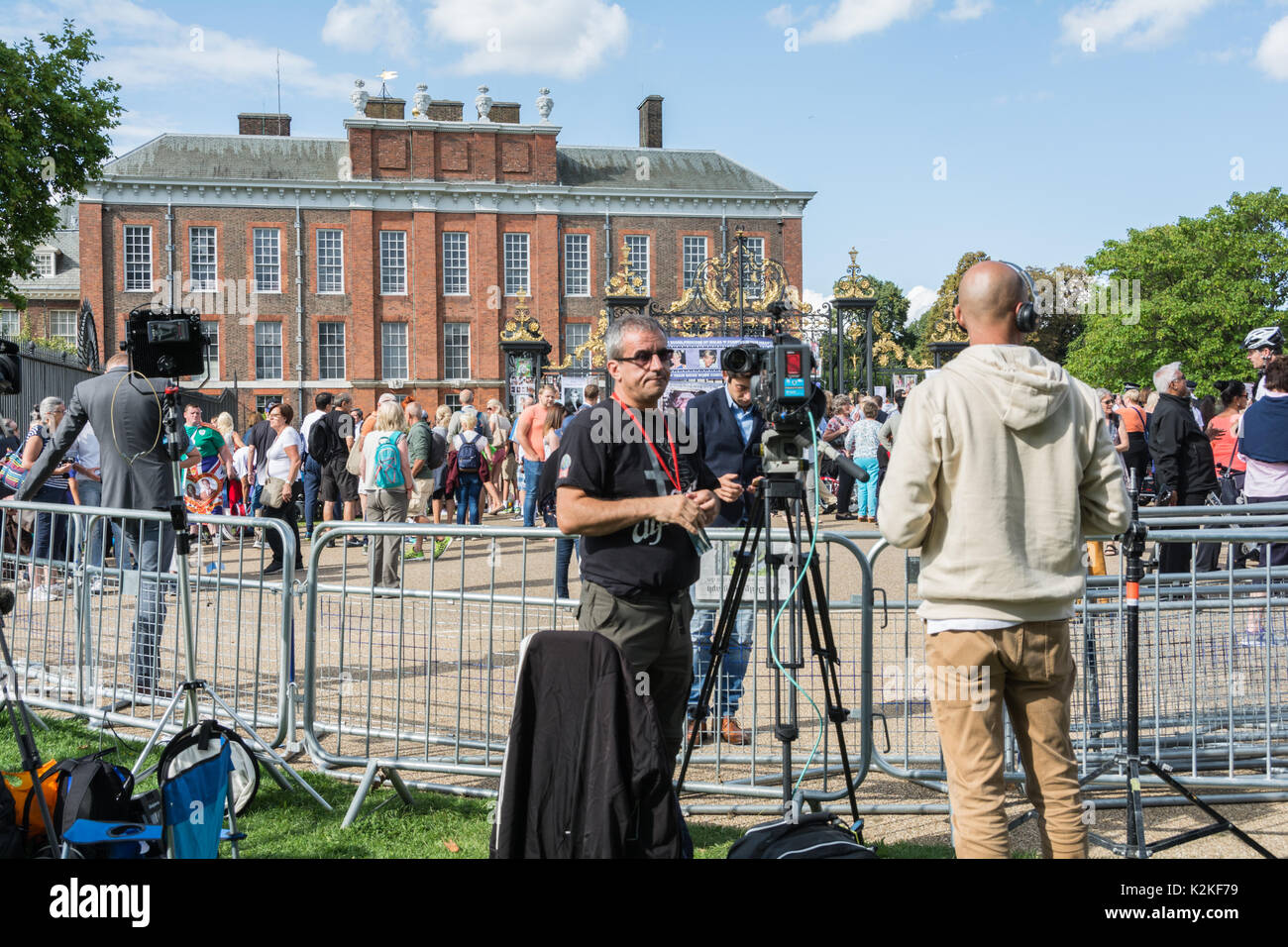 A news reporter and cameraman with a piece to camera outside the gates of Kensington Palace. Commemorating Princess Diana, twenty years after her death. Stock Photo