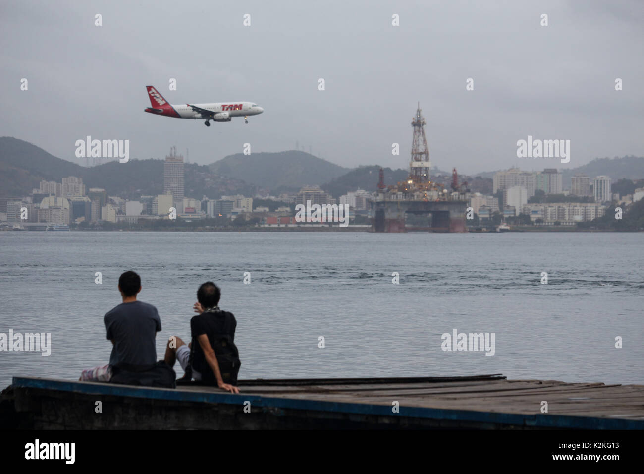 Rio de Janeiro, Brazil, August 31, 2017: End of August is marked by falling temperatures in the city of Rio de Janeiro. The thermometers marked below 20 degrees celsius. In this image men watch a plane from Latam flying over the waters of Guanabara Bay on a cold, cloudy day in downtown Rio. Credit: Luiz Souza/Alamy Live News Stock Photo