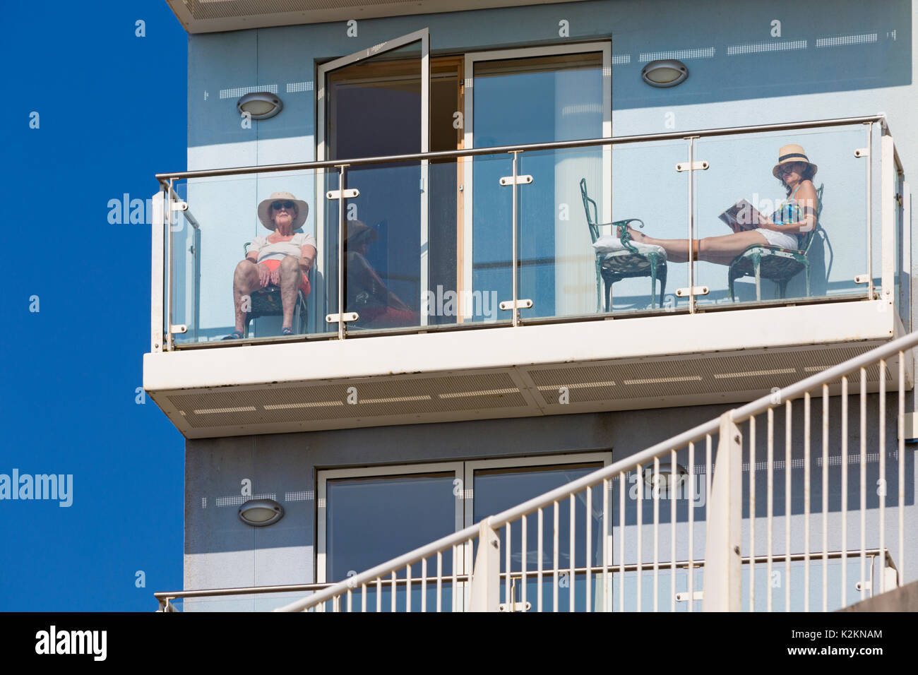 Boscombe, Bournemouth, Dorset, UK. 1st Sep, 2017. UK weather: lovely warm sunny day at Boscombe, where these women have a good view of the Bournemouth Air Festival from their apartment balcony. Woman reading Kathy Reichs Speaking in Bones book. Credit: Carolyn Jenkins/Alamy Live News Stock Photo