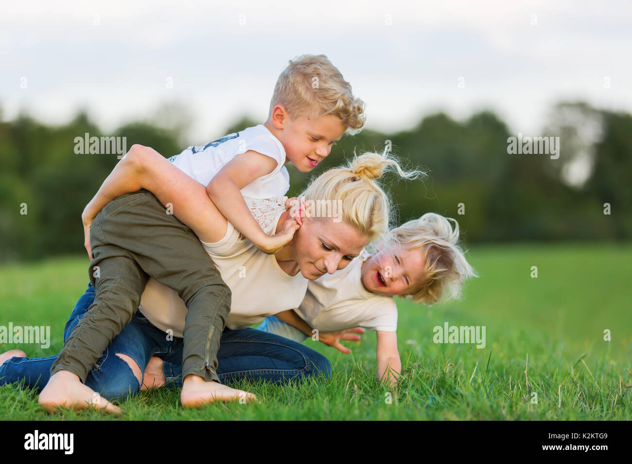 picture of a woman who romps with her two sons on the grass Stock Photo ...