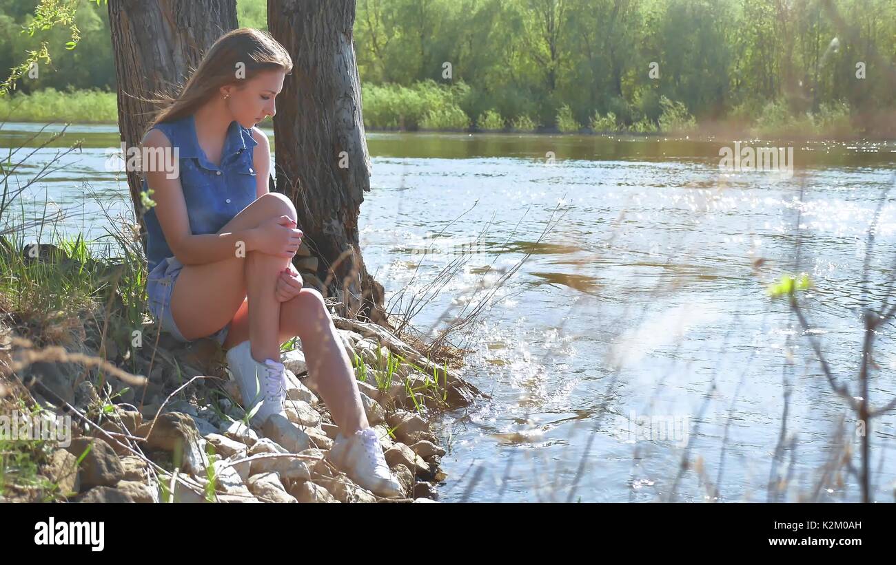 Girl on the river bank. Woman sits by the water nature lifestyle Stock ...
