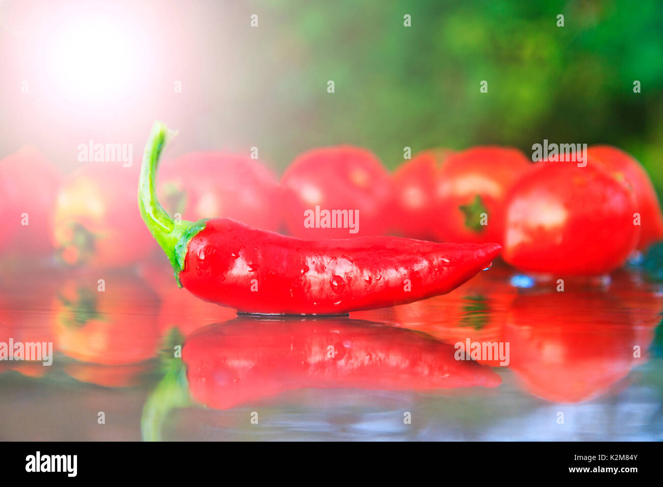 Red hot pepper on the table against the background of tomatoes Stock Photo