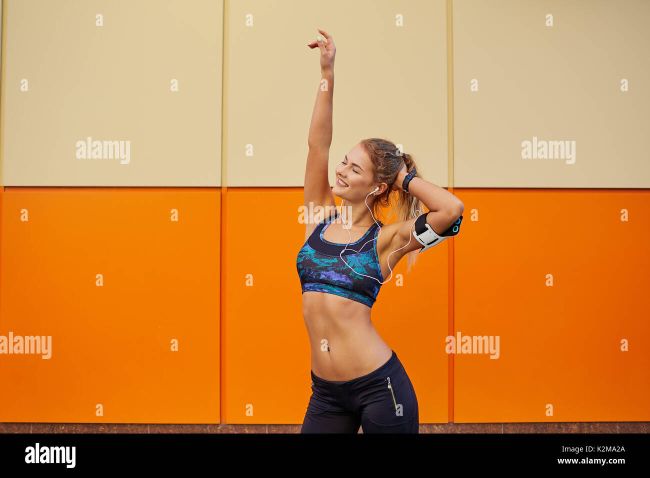 The sports girl raised her hands up on an orange background. Stock Photo