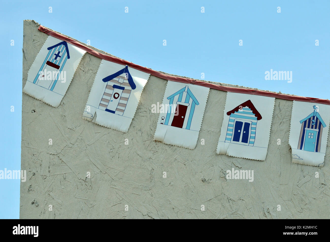 some flags or bunting on the side of a beach hut showing beach huts and a coastal theme of the seaside seashore nautical coastline marine maritime Stock Photo