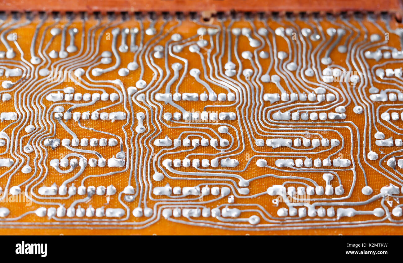Vintage circuit board with soldering trace. Backside brown electronic chip retro style design. Macro view, shallow depth of field Stock Photo