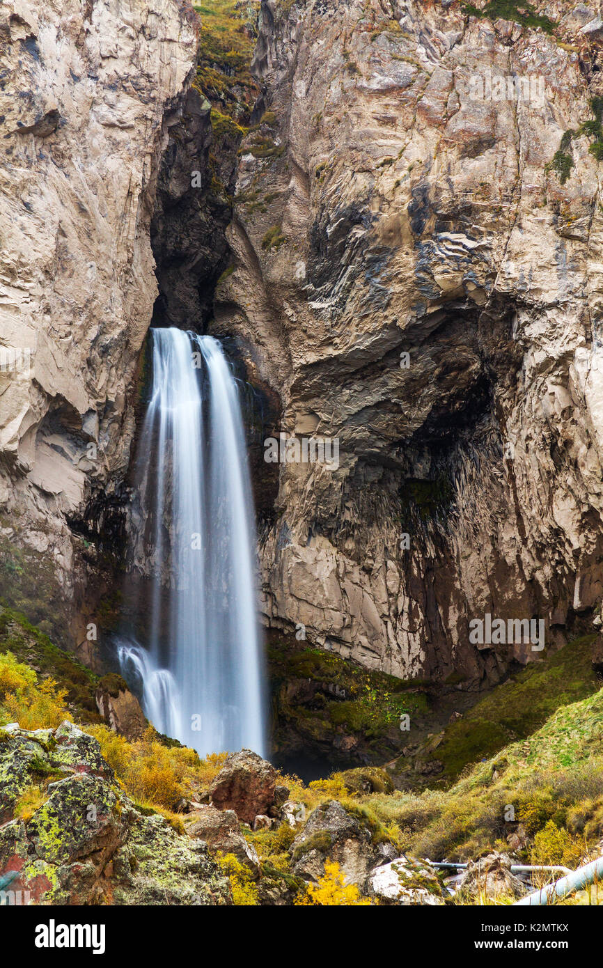 Autumn landscape: mountain stream and waterfall surrounded by stones, rocks and trees with yellow foliage. Stock Photo