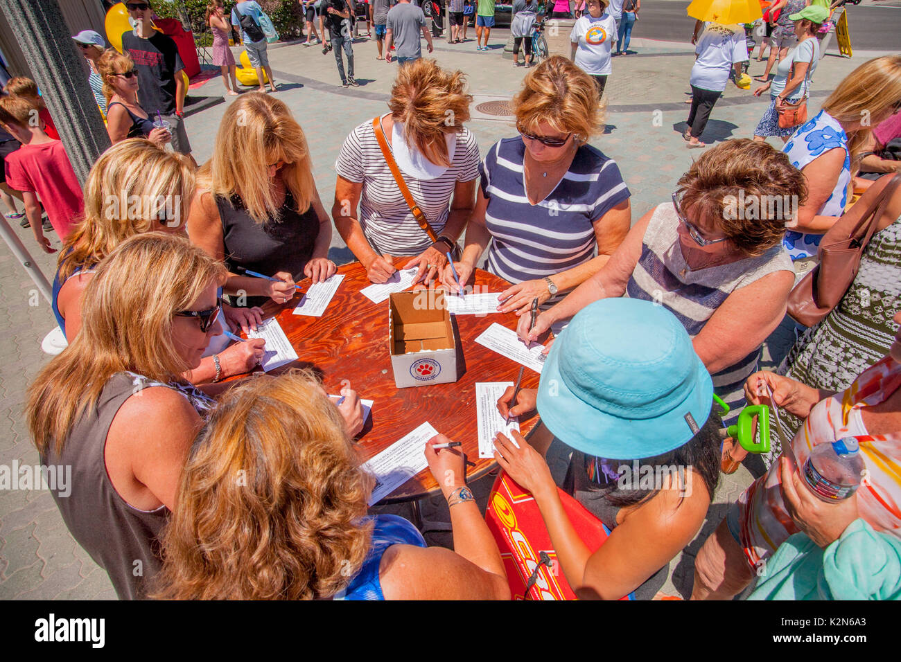 Sponsors fill out forms for plastic ducks that will drift ashore in surf from a pier in Huntington Beach, CA. Each one is numbered and sponsored and the first one to reach shore wins its sponsor a prize. Stock Photo