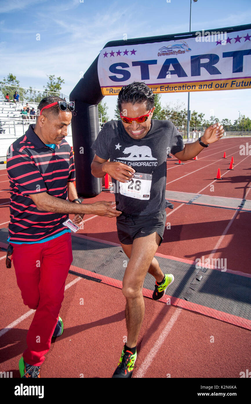 The Hispanic winner of a foot race crosses the finish line at a track