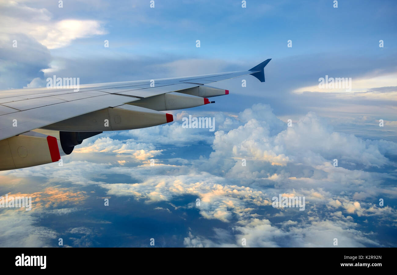 Plane wing over clouds on vibrant blue sky Stock Photo