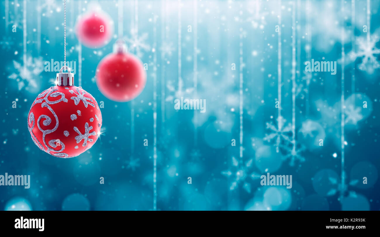 Christmas Baubles and fallen defocused snowflakes on blue background Stock Photo