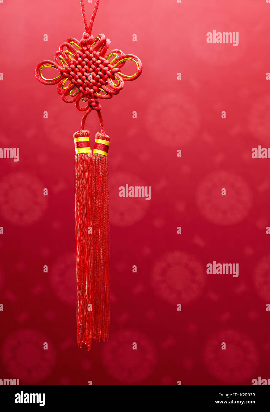 Chinese knot hanging decoration over red fabric with oriental motifs background Stock Photo