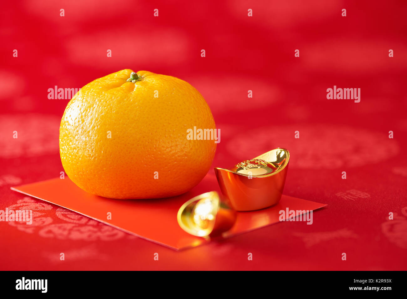 Chinese New Year - Mandarin orange, gold sycee and red packet Stock Photo