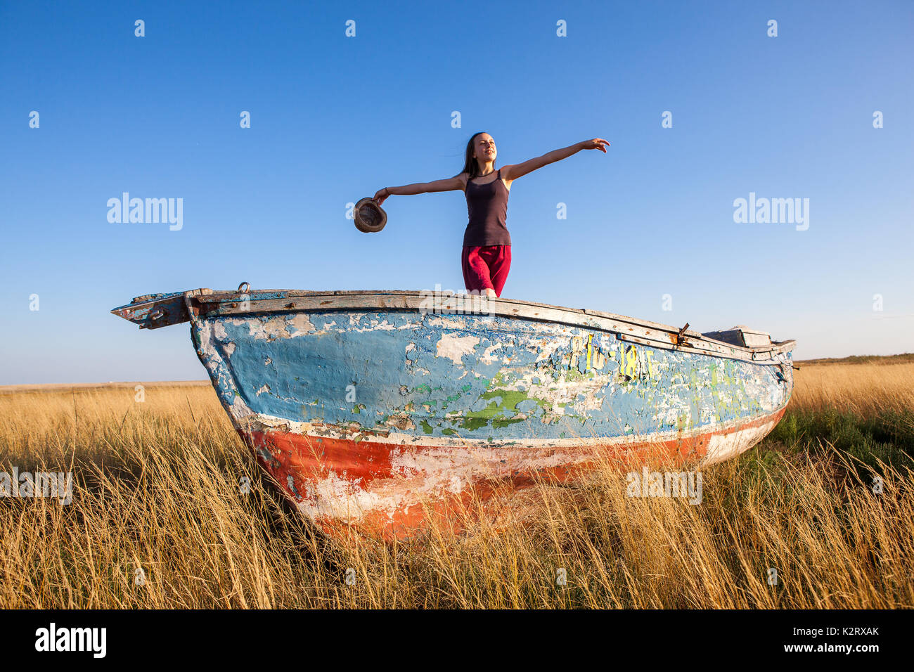 Young girl seaman floats on a boat in the field at sunset on a warm summer evening. at sunset. the dream of travel Stock Photo