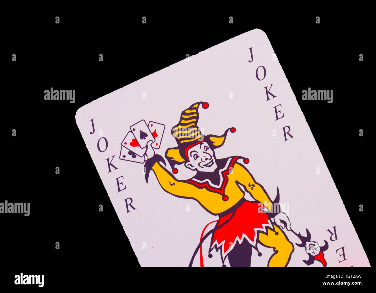 A Joker playing card set against a black background Stock Photo