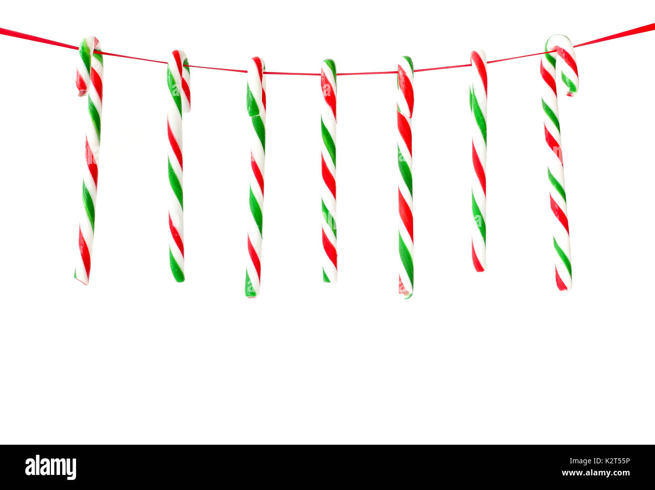 Seven red and green striped candy canes hanging on a red ribbon as