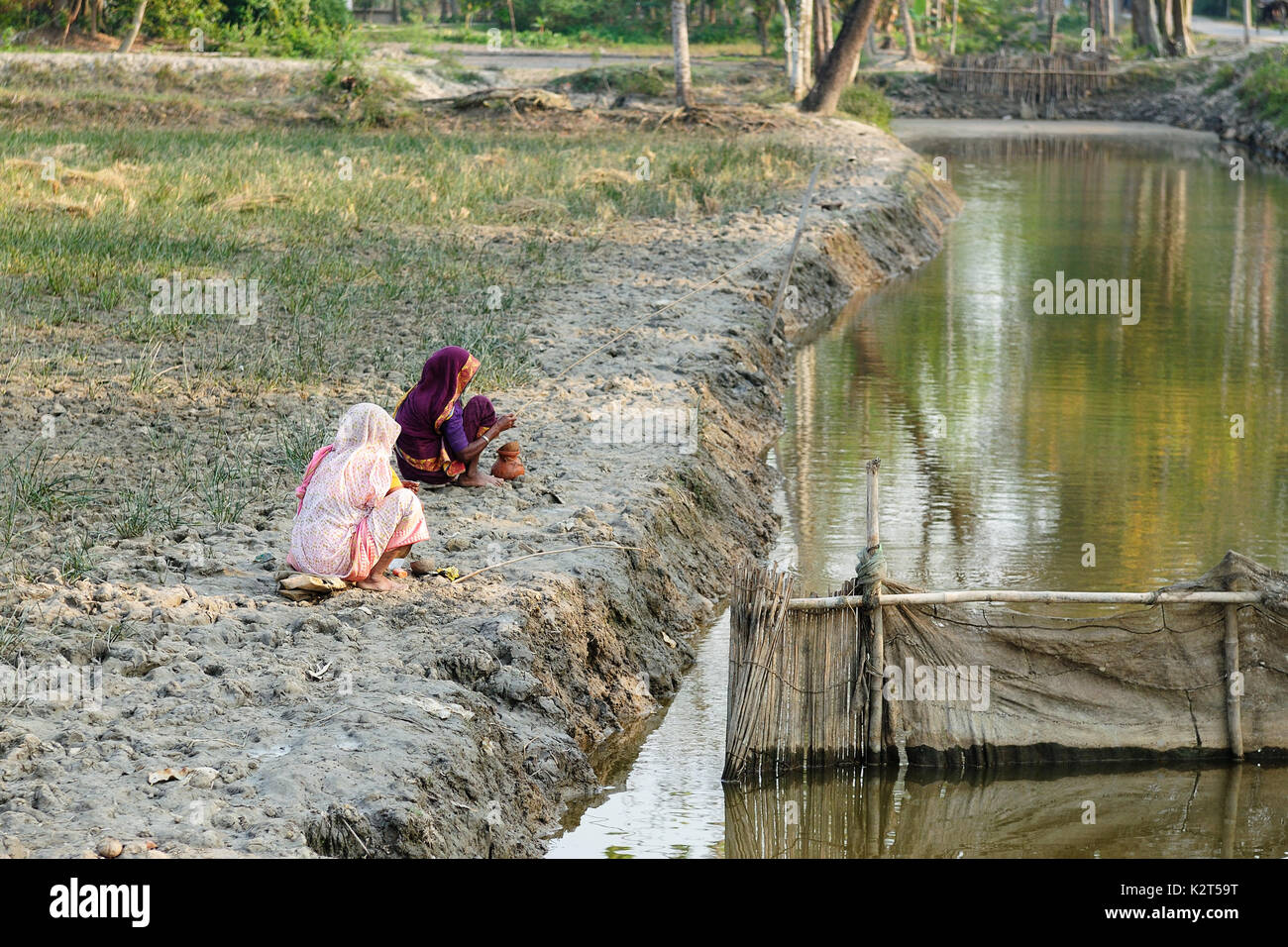 Poor Indian countrywomen fishing to the primitive fishing rod on
