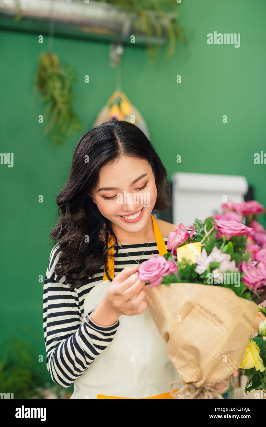 Young beautiful asian girl florist taking care of flowers at workplace. Stock Photo