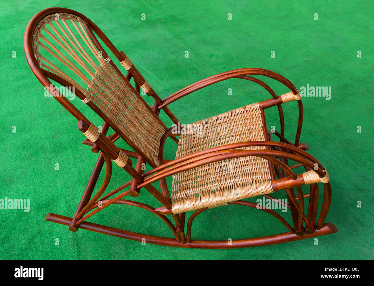 rocking chair made from natural wood and wicker on a green background