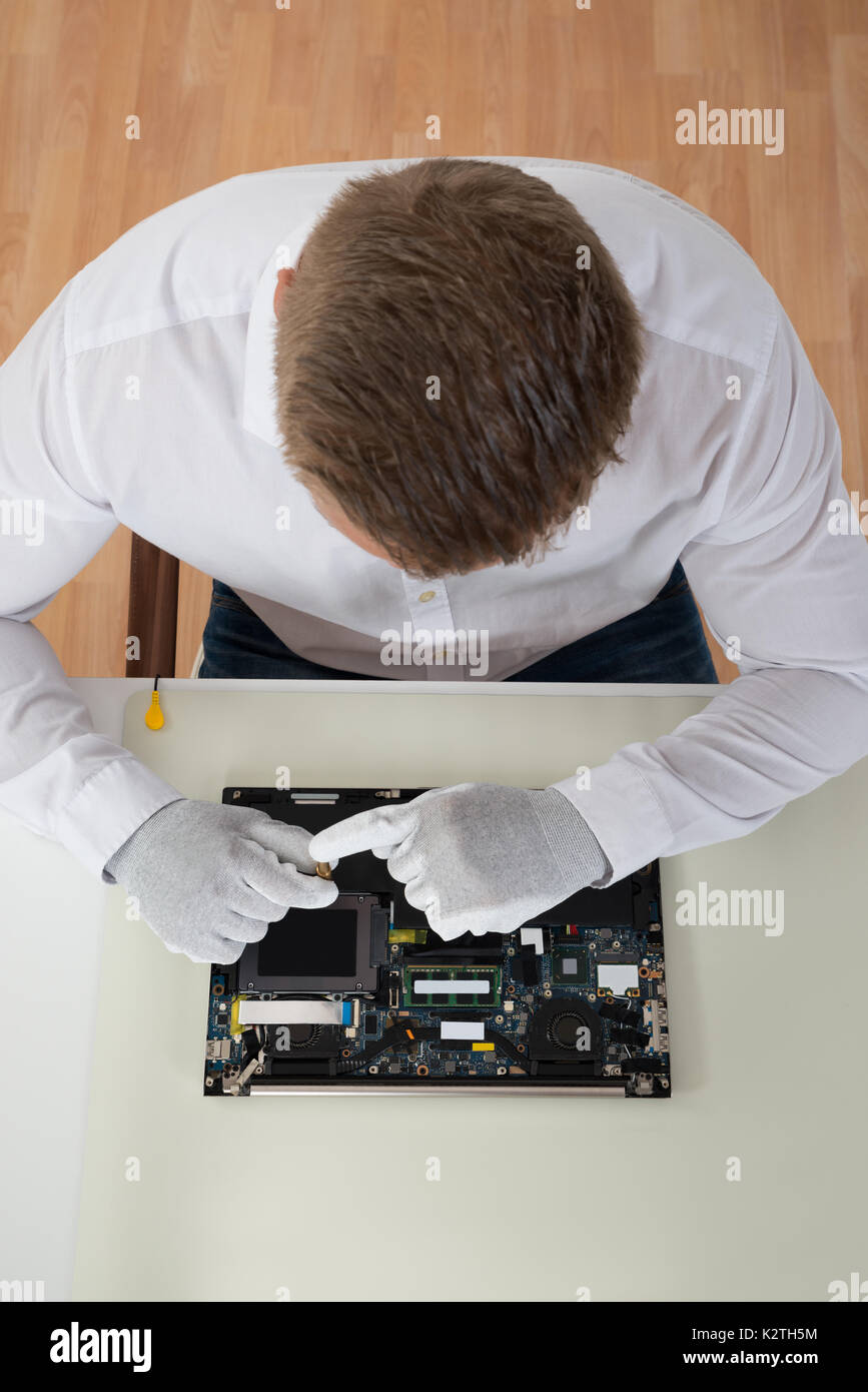 High Angle View Of Man Repairing Laptop Motherboard At Desk Stock Photo