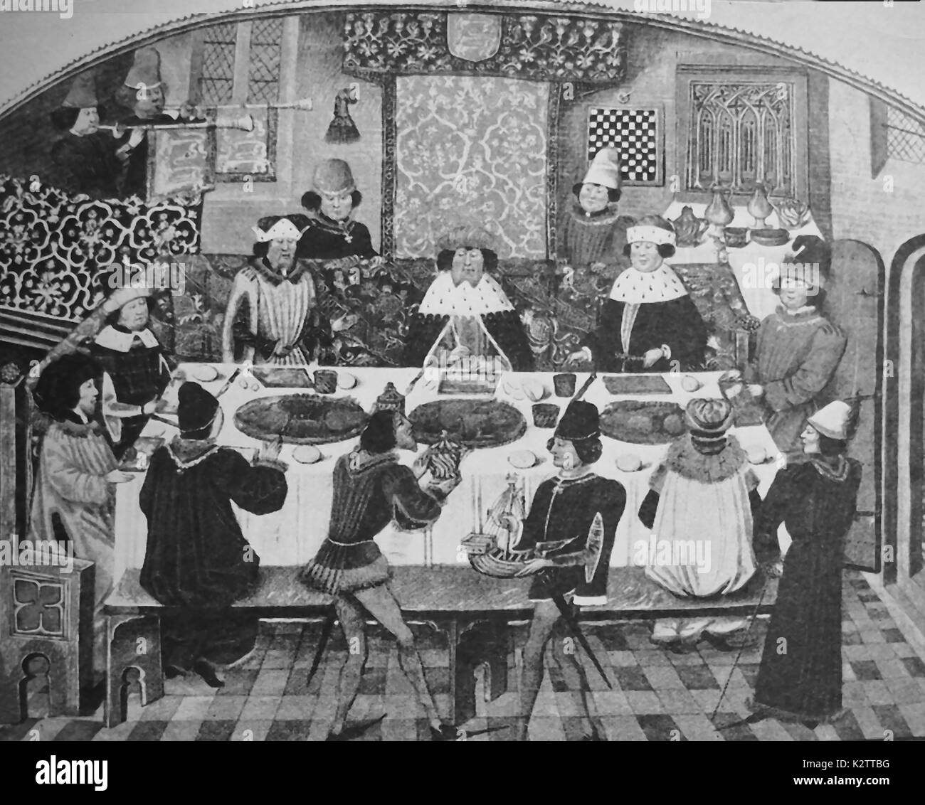 A typical high class banquet in a medieval castle dining hall showing the seating arrangement with the Lord of the manor (or a king) sitting in a plush chair at the side and with servants bringing food.(Note: knives but no forks) Stock Photo
