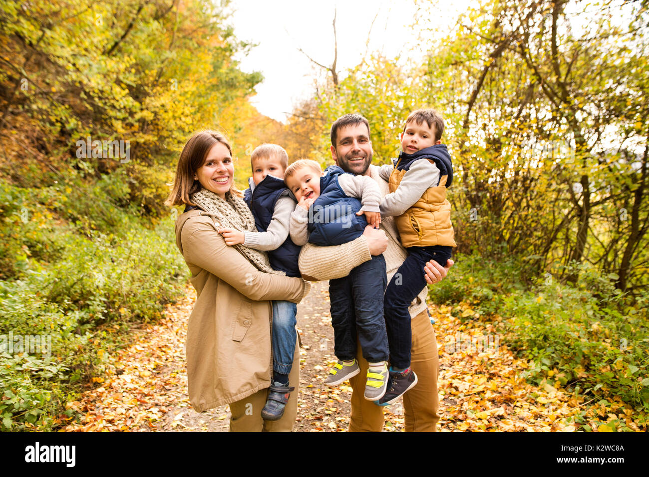 Beautiful young family on a walk in autumn forest Stock Photo - Alamy