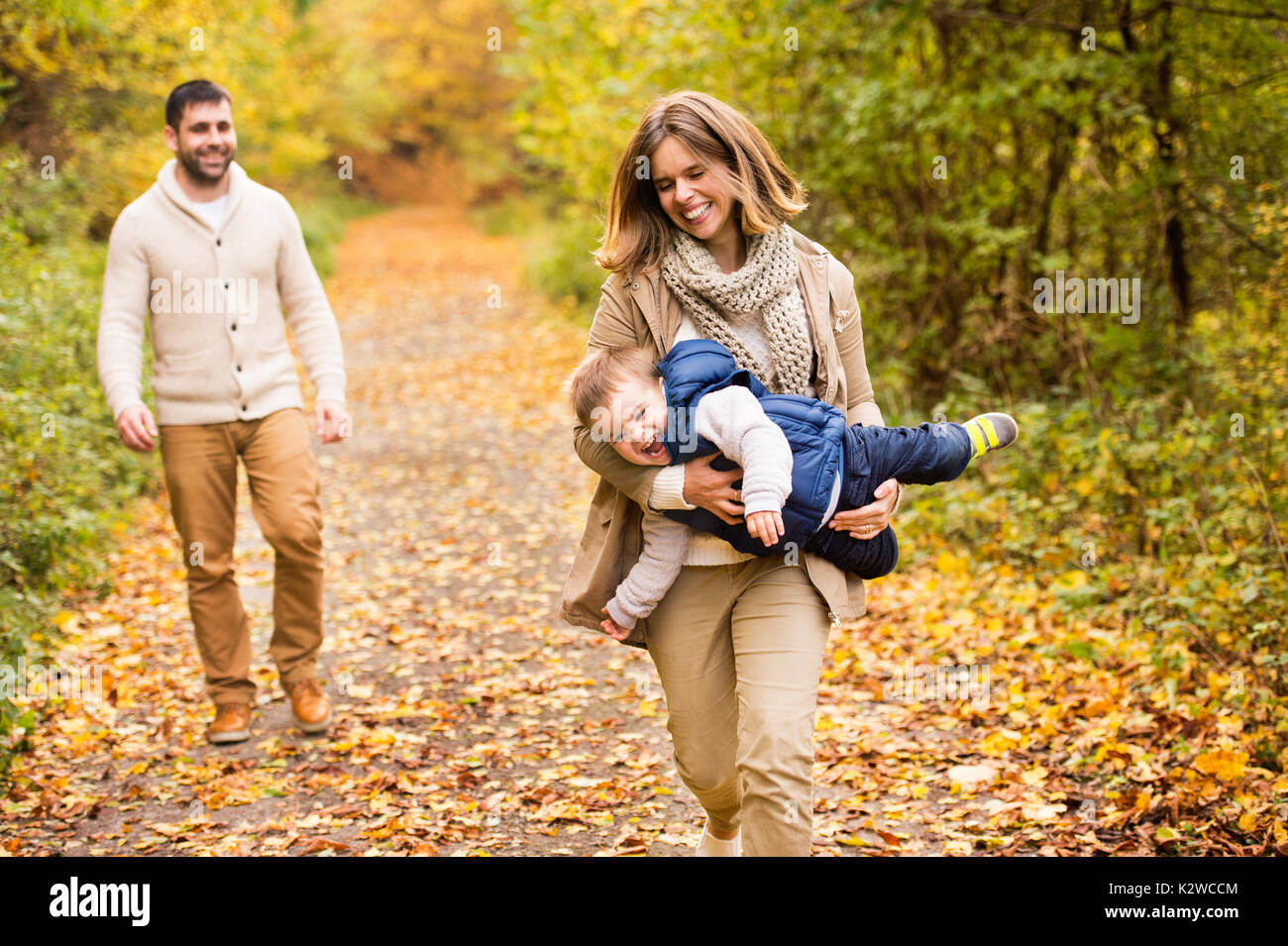 Beautiful young family on a walk in autumn forest Stock Photo - Alamy