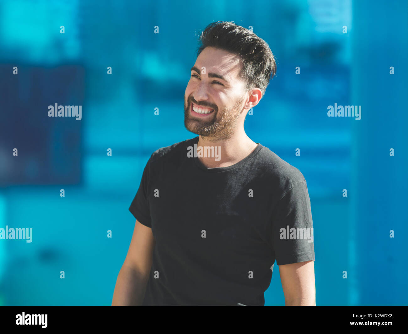 Portrait of young man laughing on blue background Stock Photo