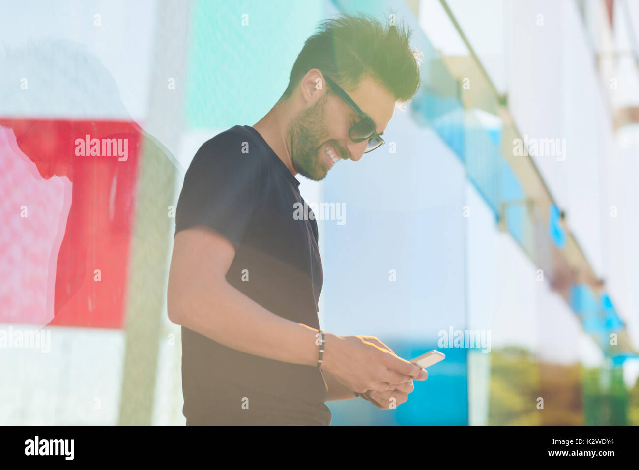 Profile portrait of laughing man in sunglasses using mobile outside Stock Photo