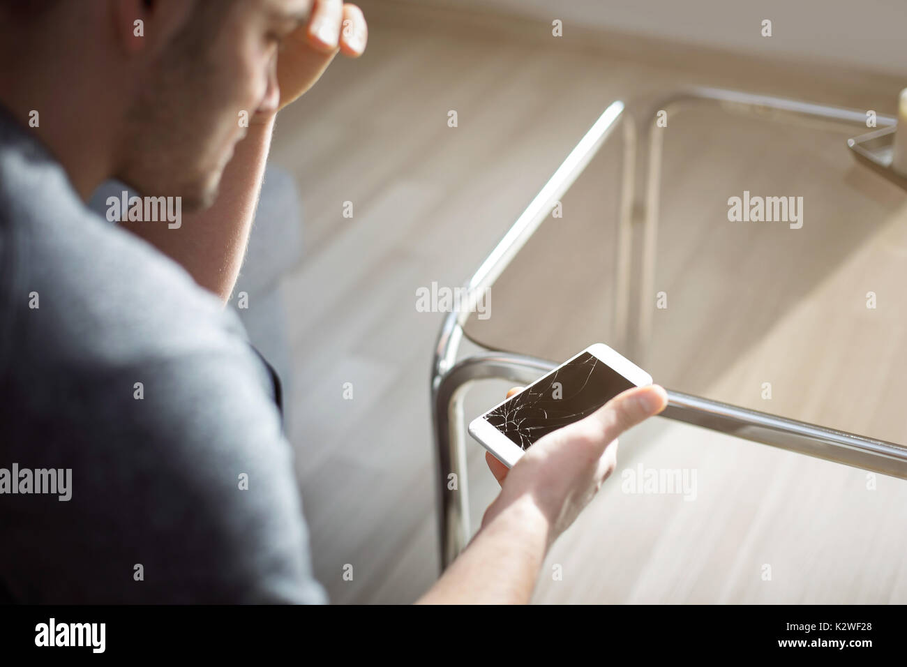 Woeful man holding damaged smart phone Stock Photo