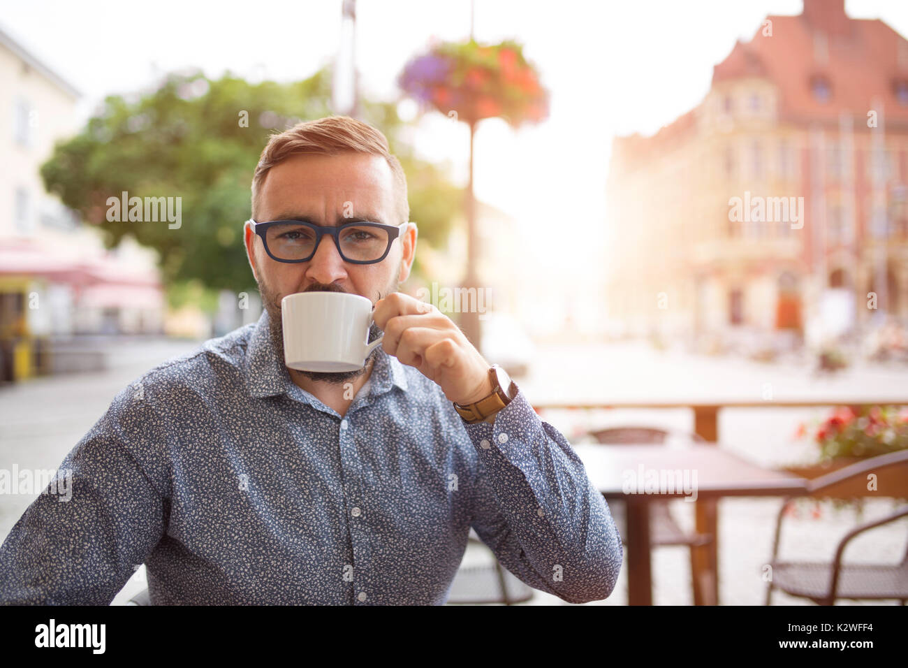 Elegant man drinking cappuccino in cafe-garden at old town Stock Photo