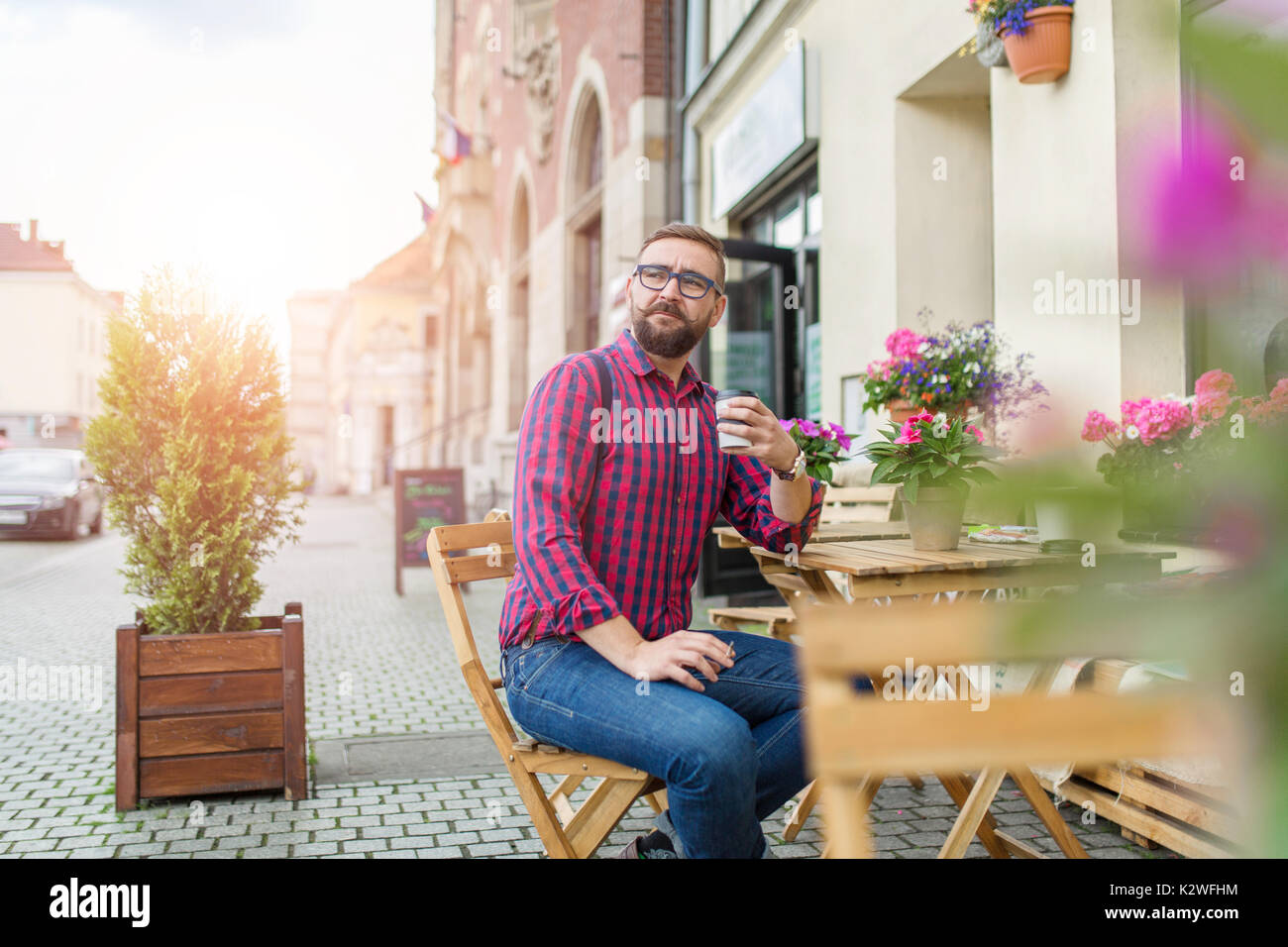 Man sitting in cafe garden and drinking takeaway coffee Stock Photo