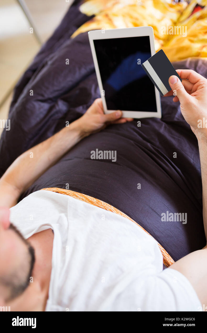 Man surfing the net on tablet in bed Stock Photo