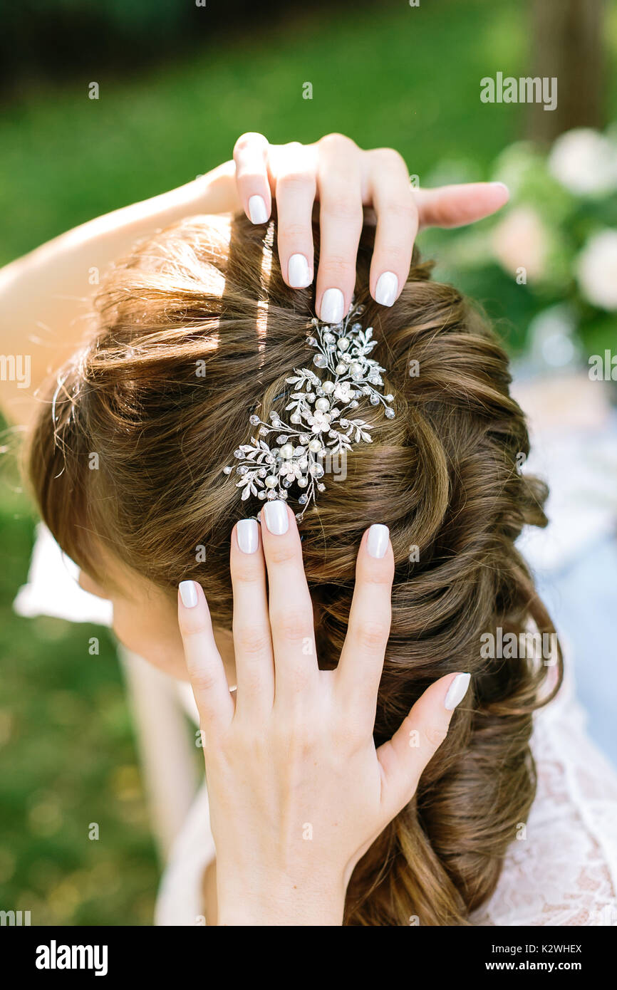 style, femininity, decoration concepr. in soft curly light brown hair of young woman there is shining barrette with diamonds in form of leaves and flowers Stock Photo