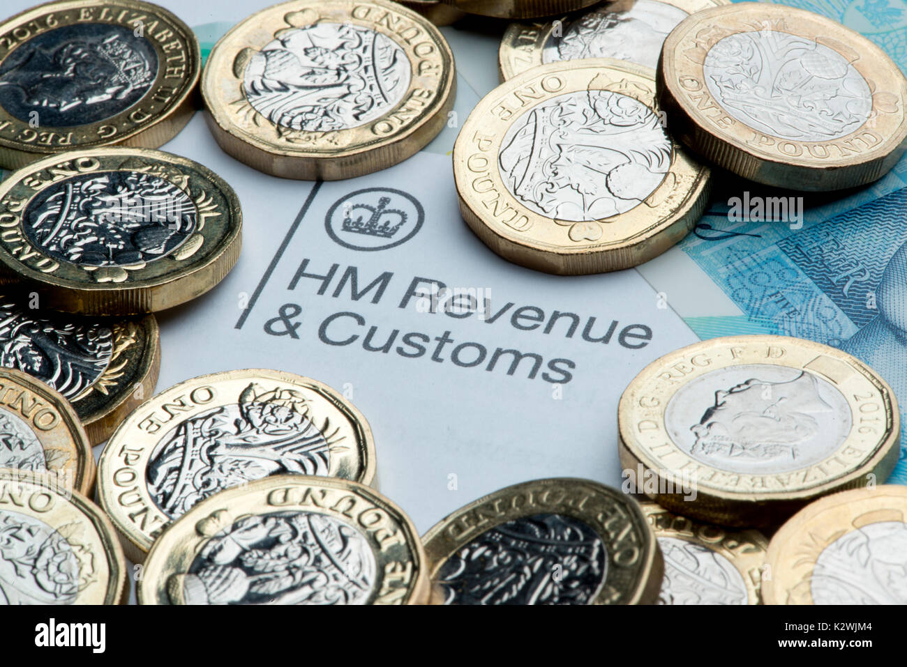 An HM Revenues & Customs letterhead surrounded by new £1 coins and a £5 note. Stock Photo