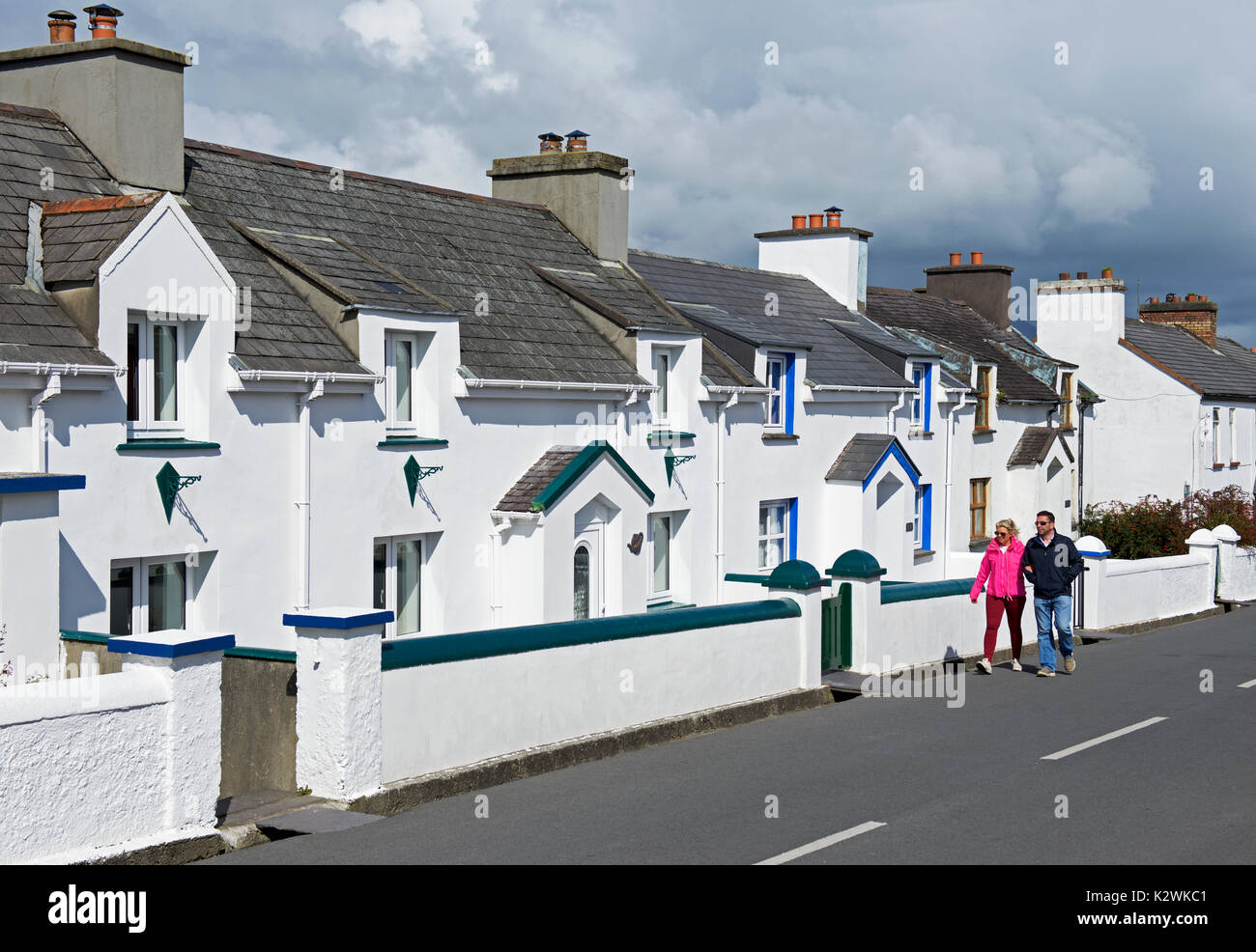 Couple passing terraced houses, Knightstown, Valentia Island,  Iveragh peninsula, Co Kerry, Southern Ireland Stock Photo