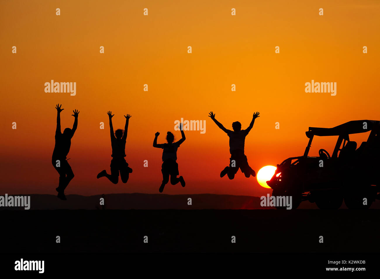 Tourists jumping at sunset on sand dunes in the desert near Huacachina Oasis, Ica, Peru, South America (MR) Stock Photo