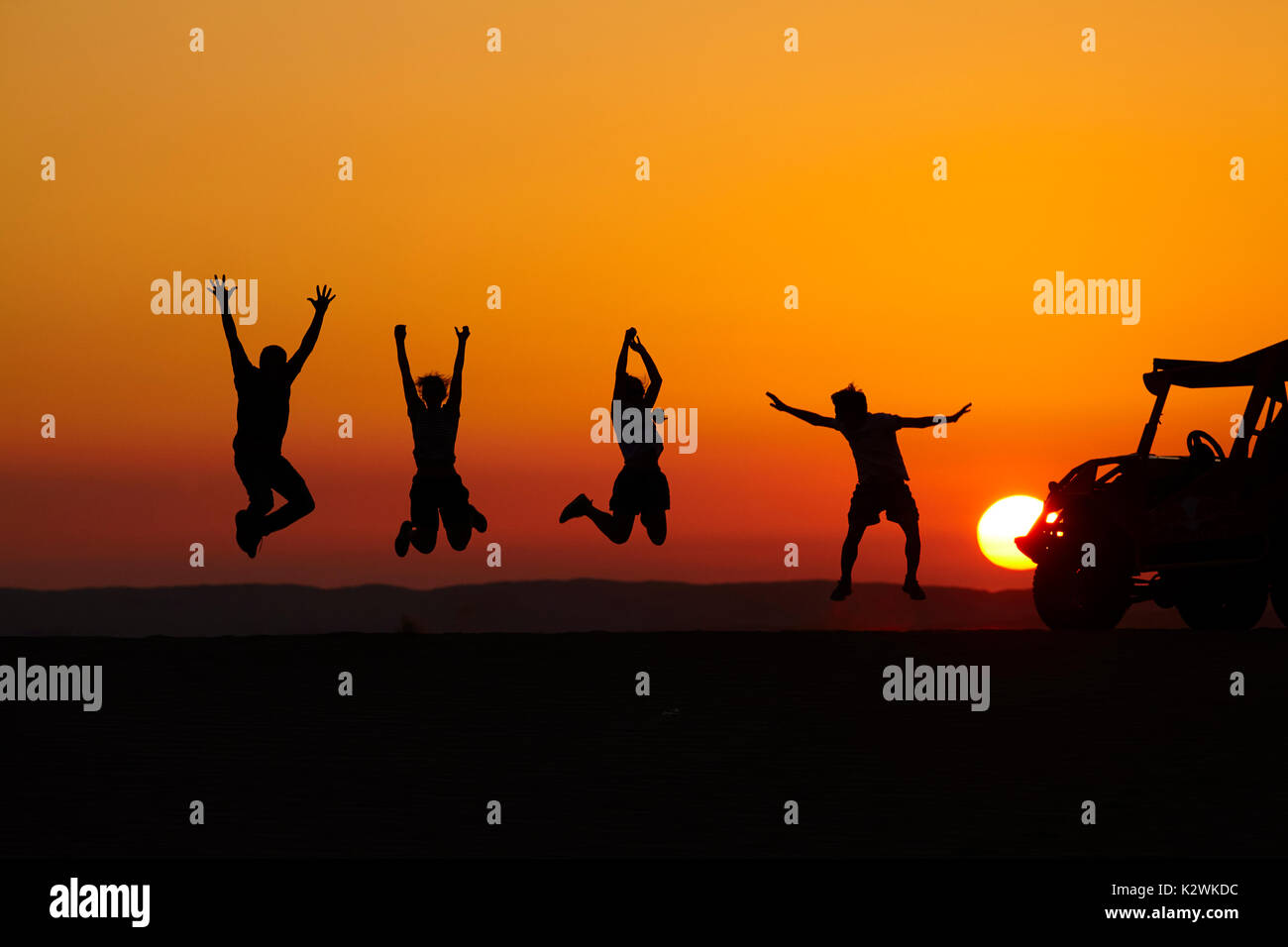 Tourists jumping at sunset on sand dunes in the desert near Huacachina Oasis, Ica, Peru, South America (MR) Stock Photo