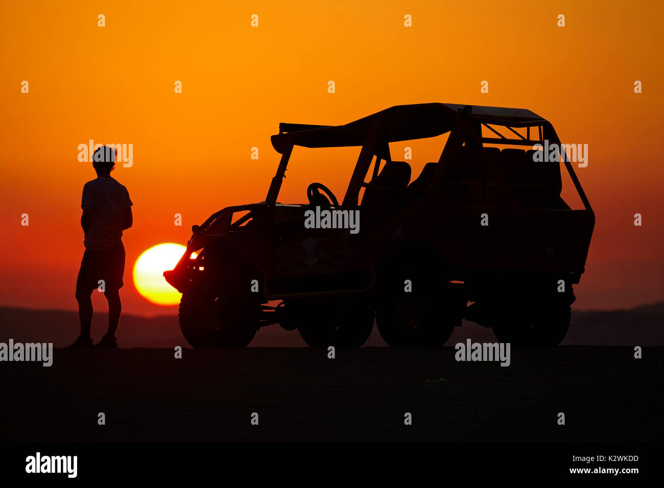 Dune buggy and tourist watching the sun set across sand dunes in the desert near Huacachina Oasis, Ica, Peru, South America (MR) Stock Photo