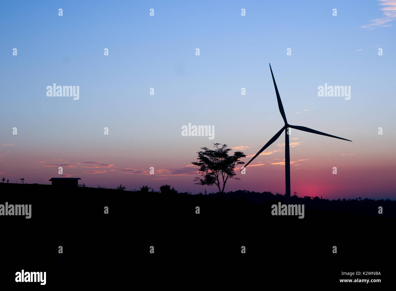 A solitary Wind Turbine silhouetted against a dramatic sunset sky ...