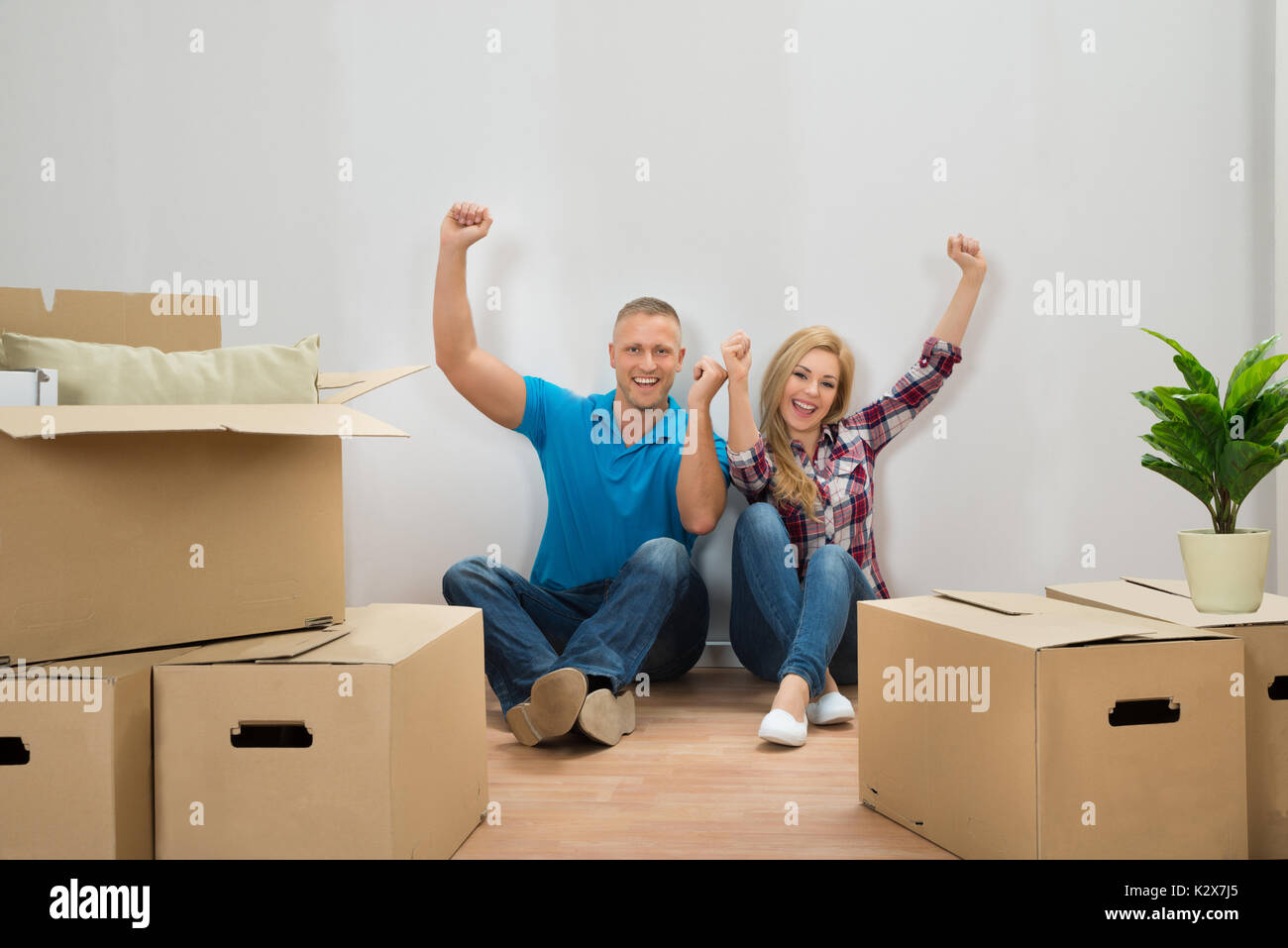 Portrait Of Excited Young Couple With Cardboard Boxes In New Home Stock Photo