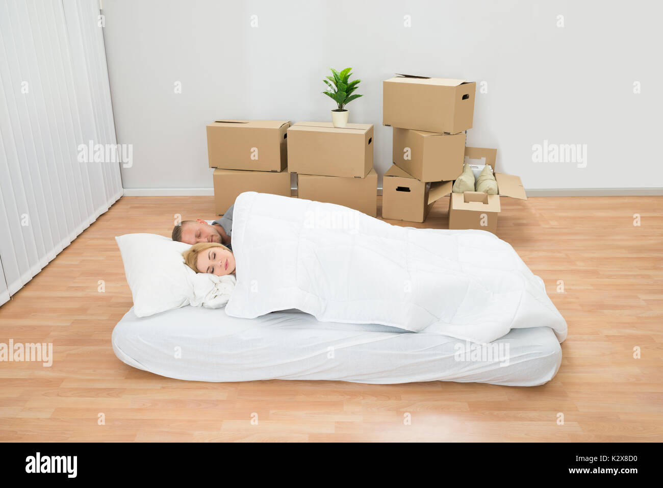 Young Couple Sleeping On Mattress In New Home Stock Photo
