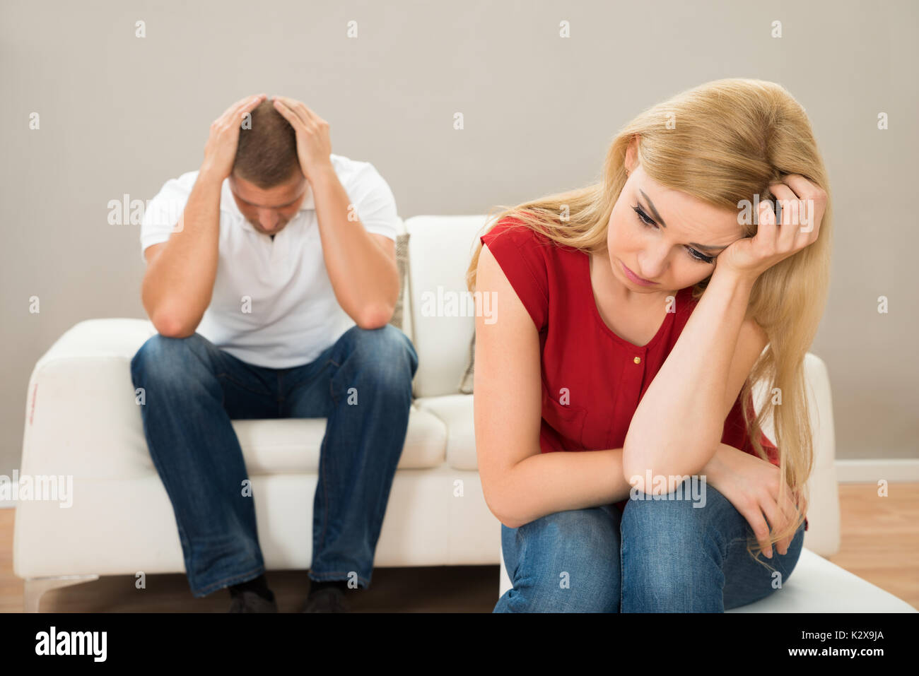 Young Man On Sofa Looking At Stressed Woman Stock Photo