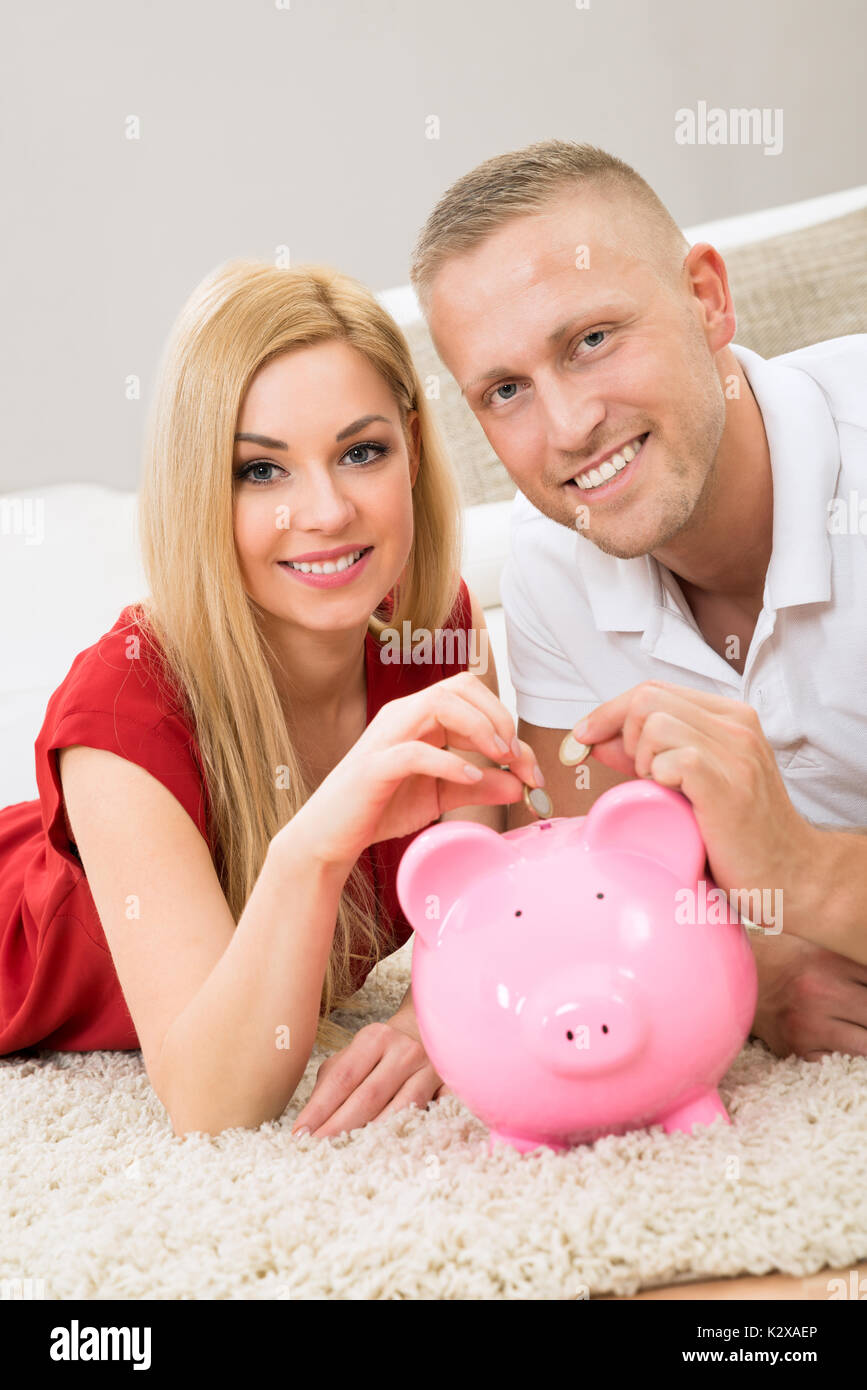 Portrait Of Happy Young Couple Inserting Coin In Piggybank Stock Photo ...