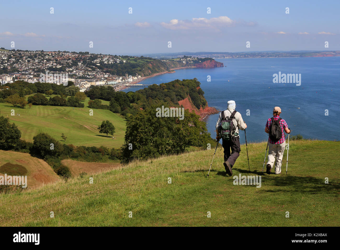 A pair of ramblers enjoy the view along the South West Coast Path looking over Ness Cove and Teignmouth, Devon, UK Stock Photo
