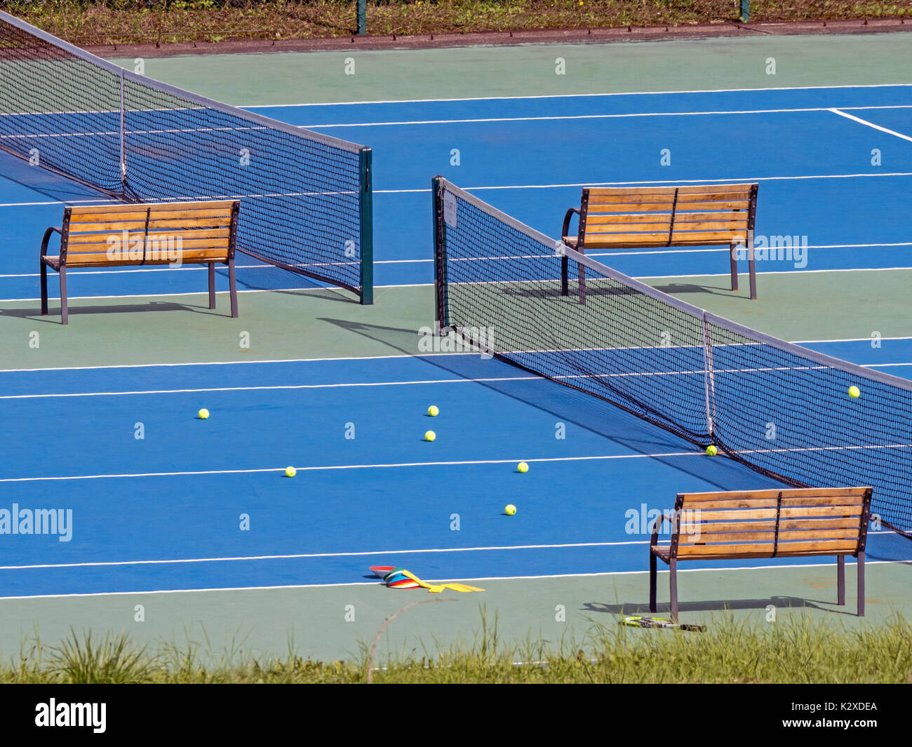 Blue surfaced tennis court with yellow balls during coaching session Stock Photo