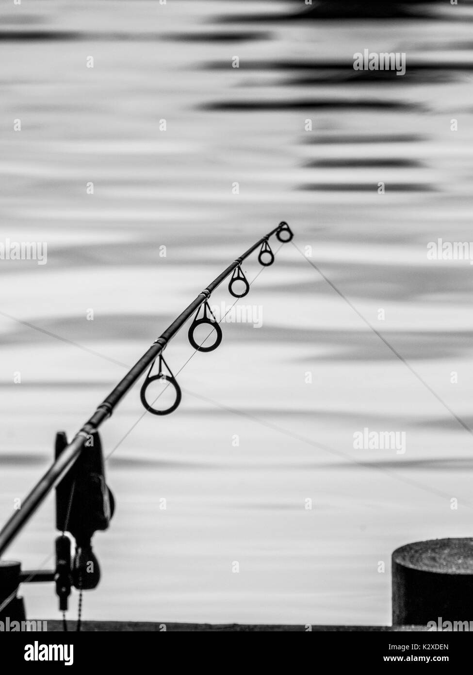 Single fishing rod stretching out over a lake Stock Photo